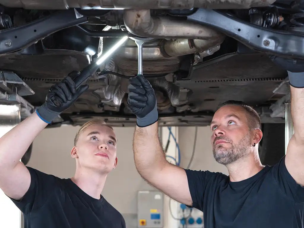 KFZ Mechaniker unter dem Auto am arbeiten